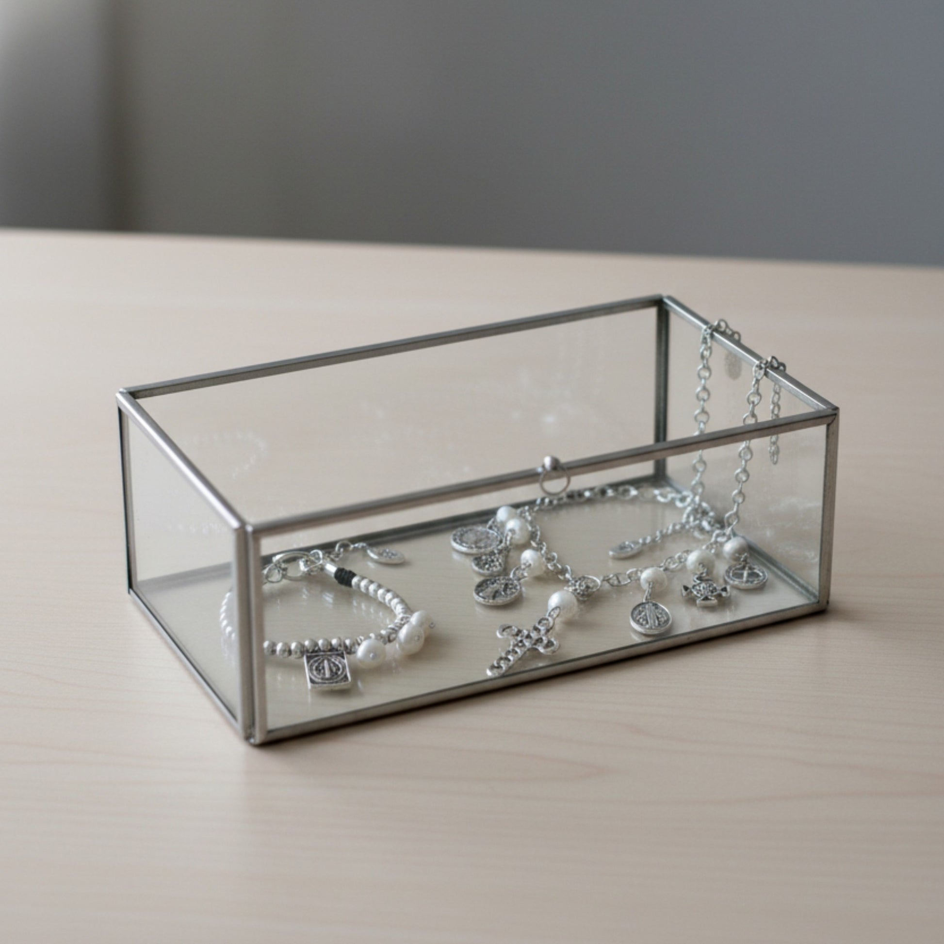 Collar y pulsera San Benito de Maldita Rita joyería, medallitas con perlas naturales en un joyero de cristal.