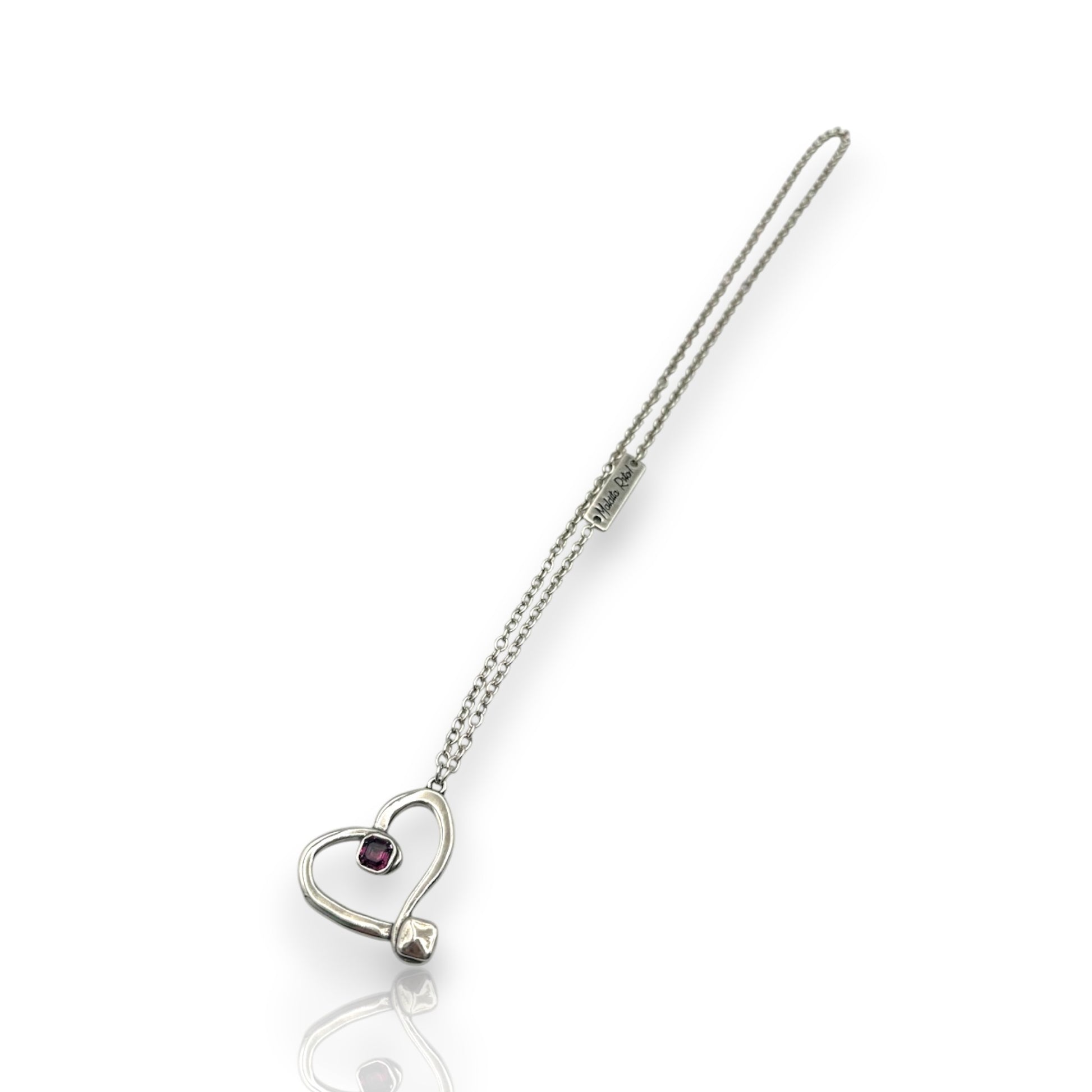 Colgante en plata en forma de corazón hueco con un cristal de Swarovsli auténtico y el logo de Maldita Rita, en color morado, vista completa.