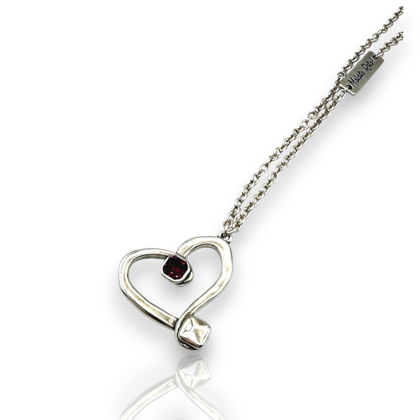 Colgante en plata en forma de corazón hueco con un cristal de Swarovsli auténtico y el logo de Maldita Rita, en color morado, detalle del colgante.