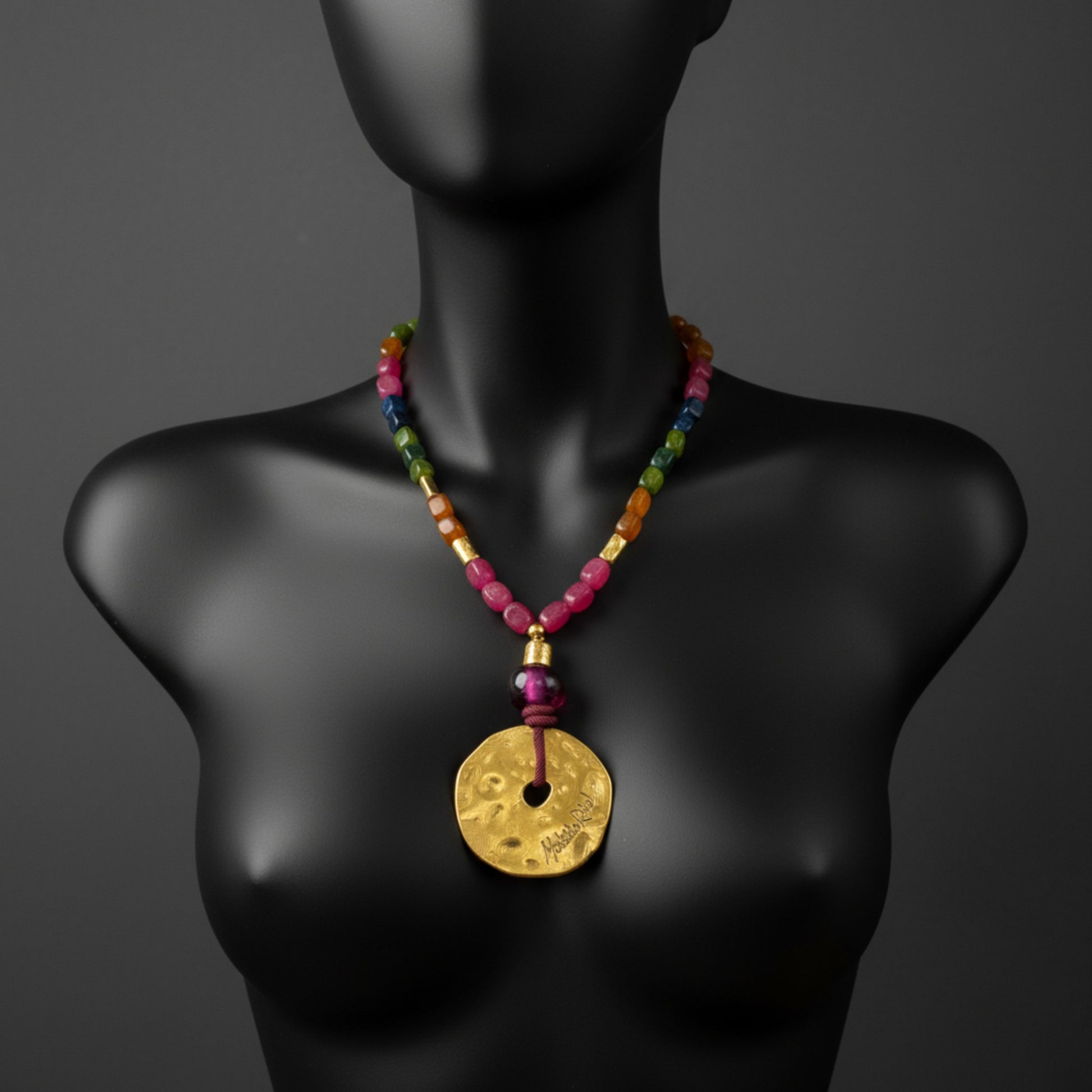 Collar corto con medallón dorado y piedas naturales de Maldita Rita Joyería.  Sobre maniquí on cabeza en negro