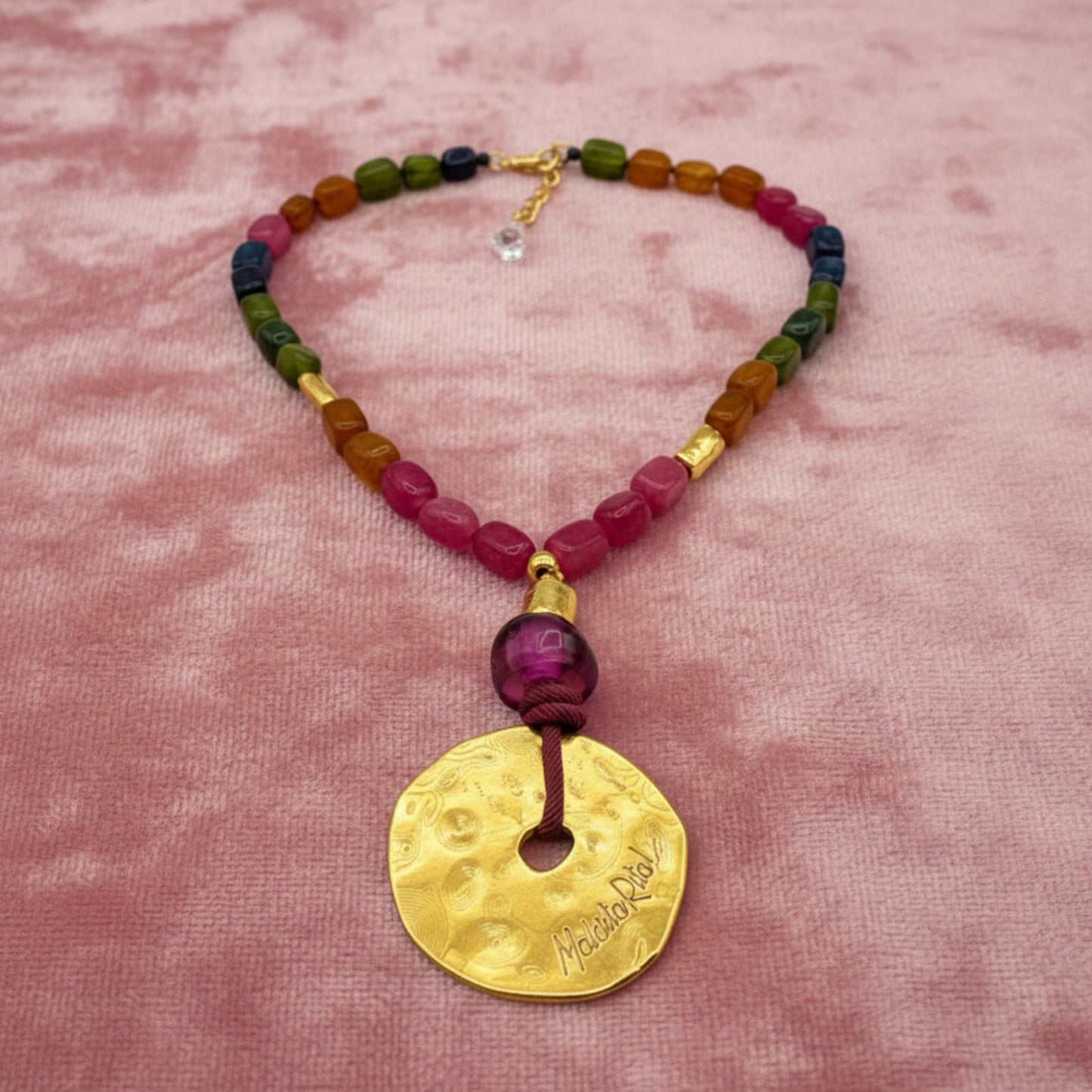 Collar corto con medallón dorado y piedas naturales de Maldita Rita Joyería.  Piedras minerales anudadas sobre tercopelo rosa