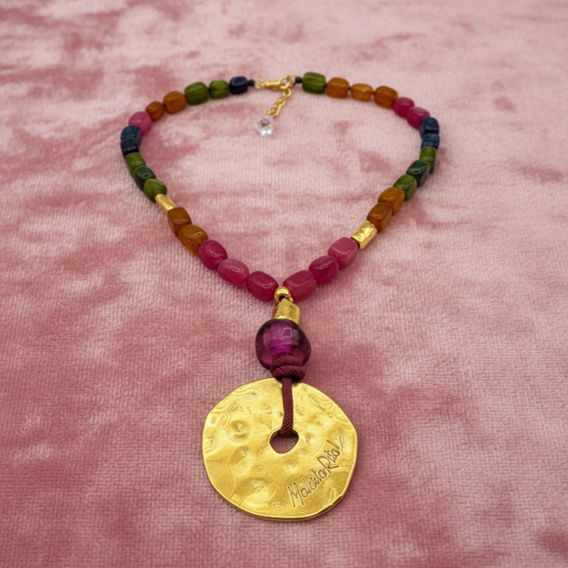 Collar corto con medallón dorado y piedas naturales de Maldita Rita Joyería.  Piedras minerales anudadas sobre tercopelo rosa
