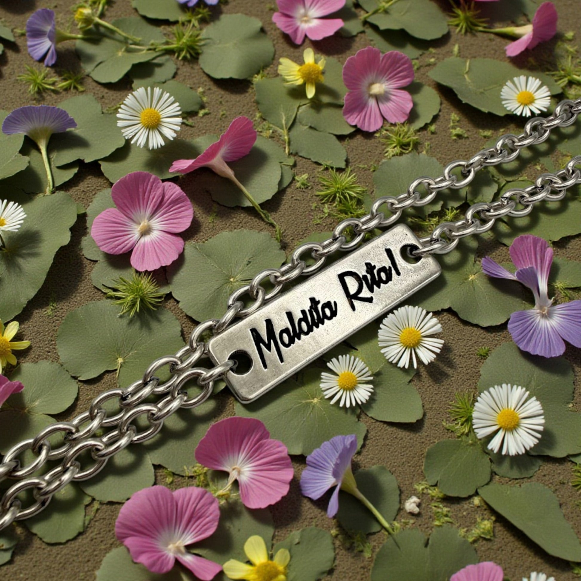 Detalle del colgante Tesoro chapita plata con el logo de la marca Maldita Rita.