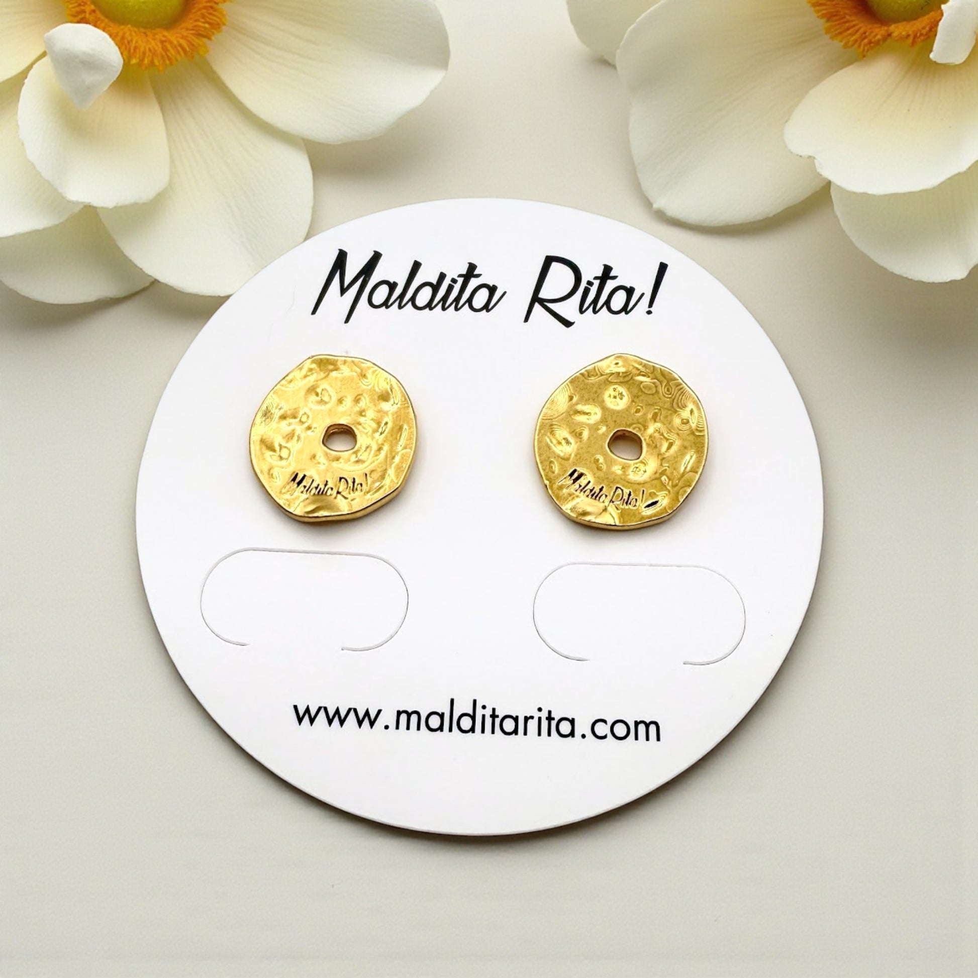 Pendientes Lunática oro de Maldita Rita, redondos irregulares, detalle vistos en expositor con flores