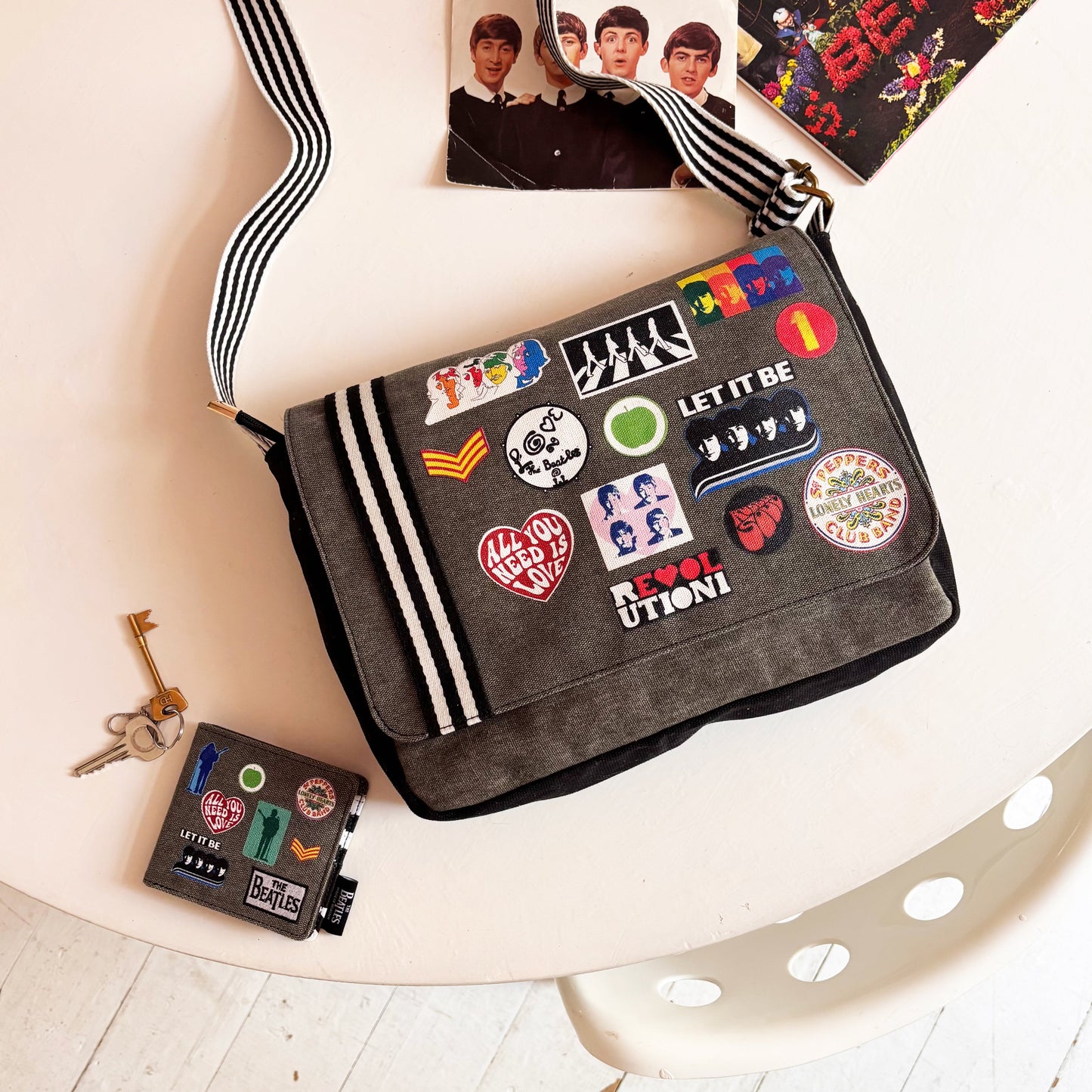 Bolso bandolera oficial The Beatles Abbey Road con parches de álbumes Beatles, venta en Maldita Rita. Junto a billetera de la colección.